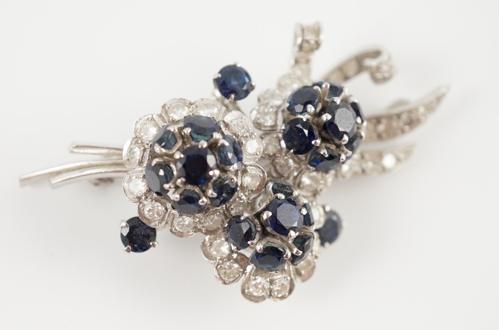 A white gold, sapphire and diamond cluster set floral spray brooch